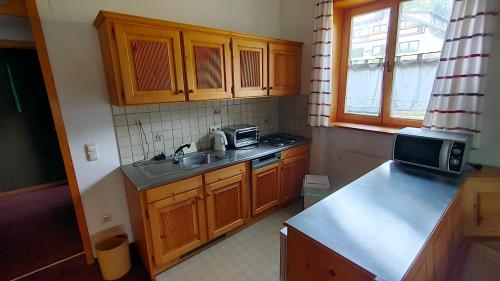 a kitchen with wooden cabinets and a sink and a microwave at FerienFleckl in Warmensteinach