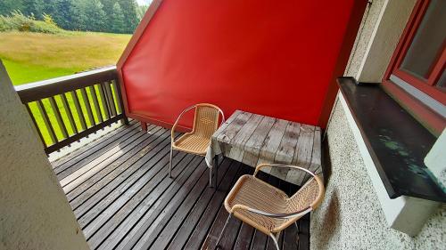 a porch with a wooden table and two chairs at FerienFleckl in Warmensteinach