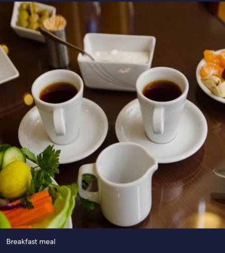 two cups of coffee on plates on a table at Italia Hotel cairo in Cairo