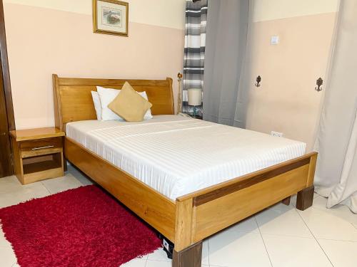 a bed in a room with a red rug at Eden Vale Hotel in Ajiringano