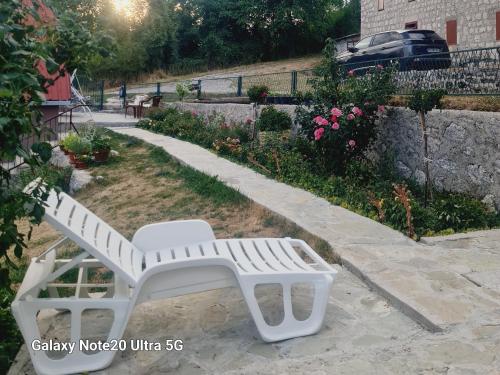 a white bench sitting in a yard next to a building at Seoski dom in Šavnik