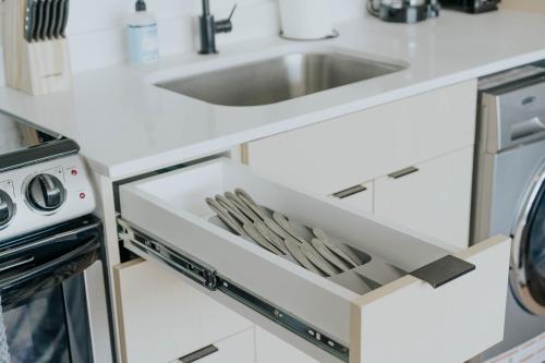 a white kitchen with a sink and a drawer at Salt City Haven in Salt Lake City