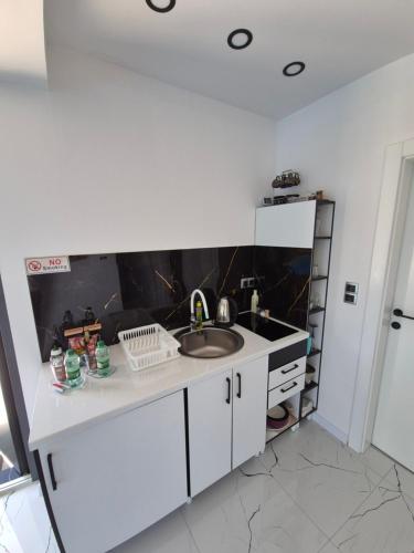 a white kitchen with a sink and a counter at Apartmani City ES in Cazin