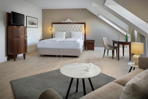 a hotel room with a bed and a living room at Arabella Jagdhof Resort am Fuschlsee, a Tribute Portfolio Hotel in Hof bei Salzburg