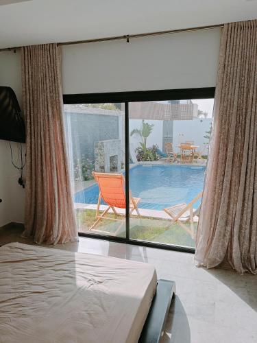 a bedroom with a large window with a view of a swimming pool at laryne in Aghīr