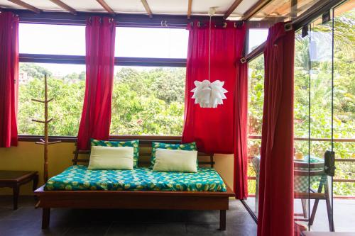 a bed in a room with windows with red curtains at Pousada Aquarela in Morro de São Paulo