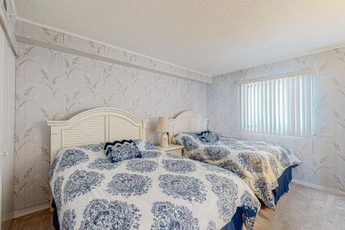 two beds in a bedroom with blue and white sheets at Plaza 909 in Ocean City