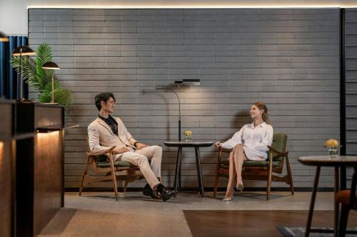two people sitting in chairs in a room at Four Points by Sheraton Bangkok, Sukhumvit 22 in Bangkok