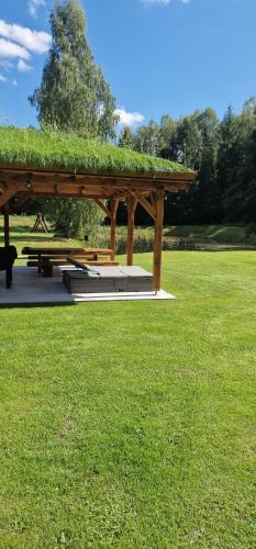 a wooden pavilion in a park with green grass at Mana Village - Jacuzzi & Sauna in Barłomino