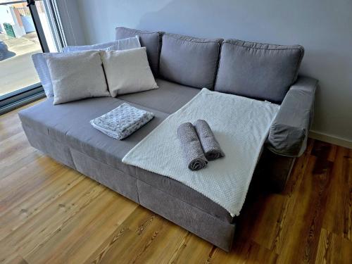 a gray couch with two pillows on a wooden floor at Lagoa Nest in Lagoa