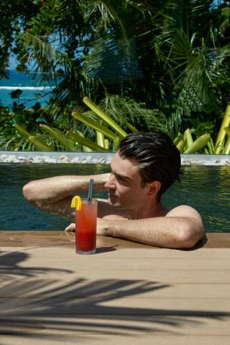 a man sitting in a pool with a drink at laïla, Seychelles, a Tribute Portfolio Resort in Mahe