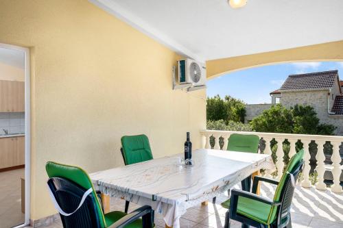 a white table and green chairs on a patio at Apartment Draga in Vir