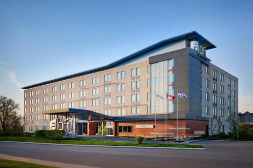 a large building with a flag in front of it at Aloft Montreal Airport in Dorval