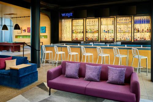 a purple couch in front of a bar with stools at Aloft Montreal Airport in Dorval