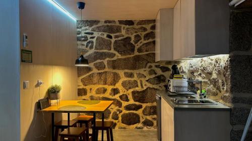 a kitchen with a stone wall and a table with chairs at Casa do Doutor - Palheiro in Mondim de Basto