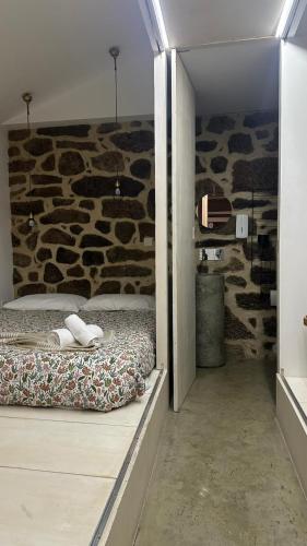 a bedroom with a bed and a stone wall at Casa do Doutor - Palheiro in Mondim de Basto