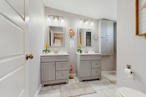 een witte badkamer met 2 wastafels en een spiegel bij Flip Flop Cottage in Rockport