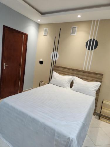a bedroom with a large bed with white sheets at E1G Meublé 1CH in Douala