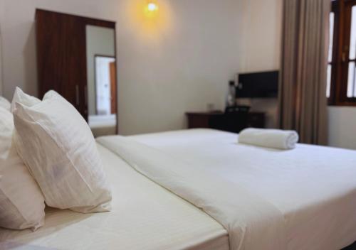 a white bed with white sheets and pillows at Kings Town Hotel in Anuradhapura