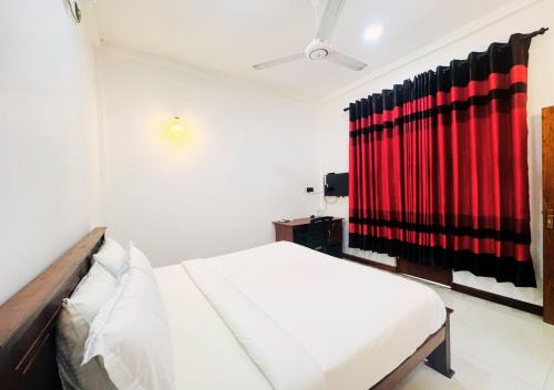 a bedroom with a bed and a red curtain at Kings Town Hotel in Anuradhapura