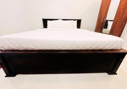 a bed with a wooden frame and a white mattress at Kings Town Hotel in Anuradhapura