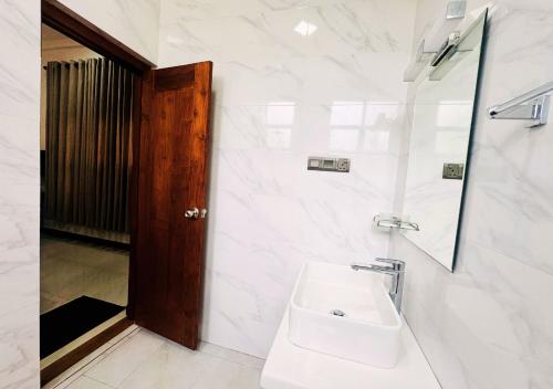 a white bathroom with a sink and a mirror at Kings Town Hotel in Anuradhapura