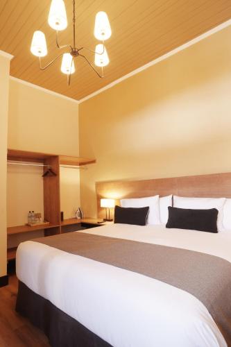 a bedroom with a large white bed with black pillows at Centenario Hotel Boutique in Quetzaltenango