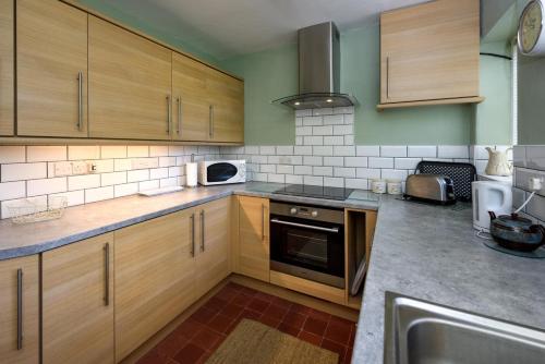 a kitchen with wooden cabinets and a stove top oven at Dolwar in Abersoch
