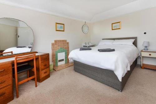 a bedroom with a bed and a dresser and a mirror at Dolwar in Abersoch