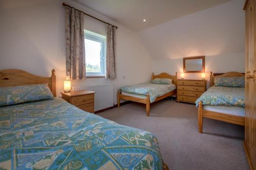 a bedroom with two beds and a window at Bragdy Wern in Llanbedrog
