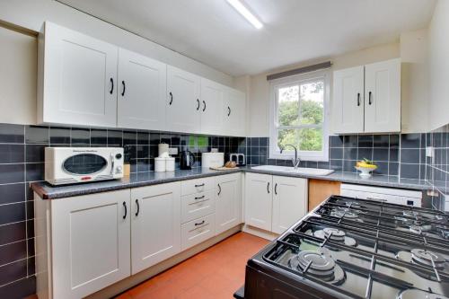 a kitchen with white cabinets and a stove top oven at Arthog Hall Farm in Arthog