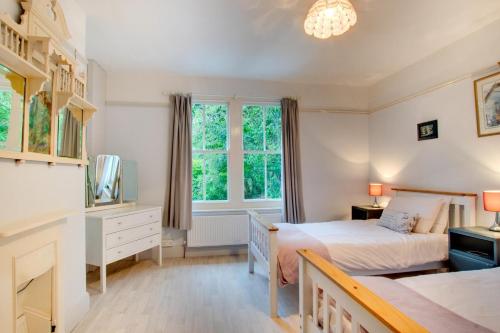 a bedroom with a bed and a desk and two windows at Arthog Hall Farm in Arthog