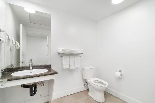 a white bathroom with a toilet and a sink at Cozy 1BR on Harrison Lake in Harrison Hot Springs