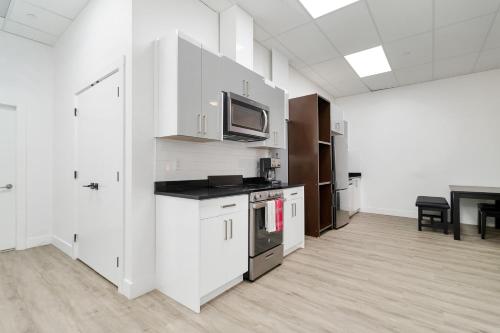 a kitchen with white cabinets and a tv on the wall at Cozy 1BR on Harrison Lake in Harrison Hot Springs