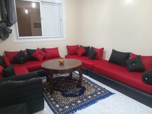 a red couch with red pillows and a table at Appartement Éco Garoutière Al massira Agadir in Agadir