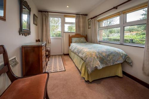 a bedroom with a bed and a dresser and windows at The Cottage in Llanbedrog