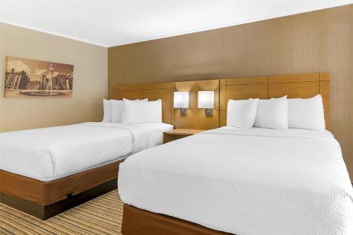 two beds in a hotel room with white sheets at Best Western Royal Plaza Hotel and Trade Center in Marlborough