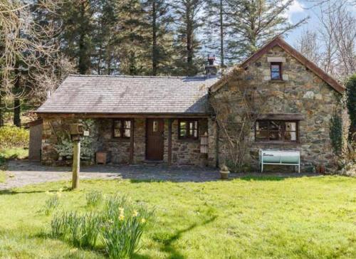 a stone house in a field of green grass at Ty Rowan in Trefriw