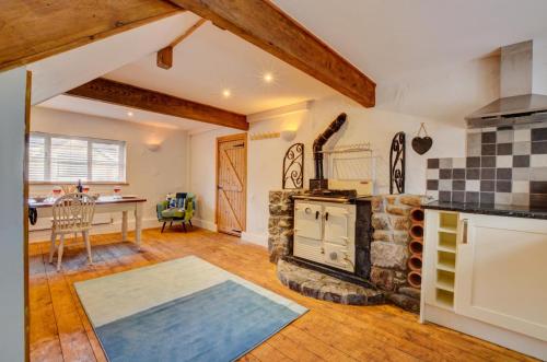 a kitchen with a stone stove and a dining room at Ty Rowan in Trefriw
