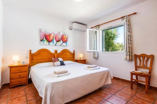 a bedroom with a large bed and a window at Villa Blanc Arenal by Villa Plus in Es Mercadal
