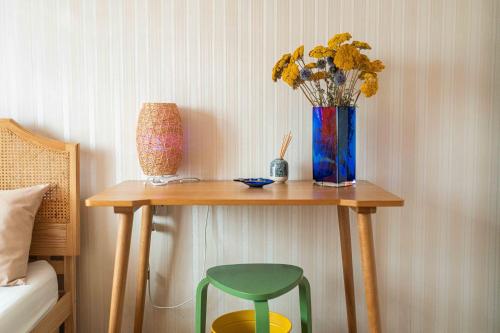 a table with a vase of flowers and a green chair at Garden Room Near Heathrow in Feltham