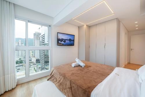 a bedroom with a large bed and a large window at Riviera Bela Vista 3 Suítes by Achei Camboriú in Itajaí