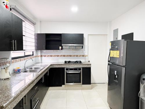a kitchen with a black refrigerator and a sink at Casa con Piscina Privada, Asadero Bbq y 4 cuartos en Guayaquil in Guayaquil