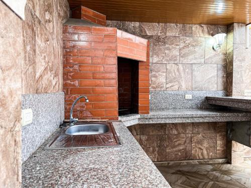 a kitchen with a sink and a brick wall at Casa con Piscina Privada, Asadero Bbq y 4 cuartos en Guayaquil in Guayaquil