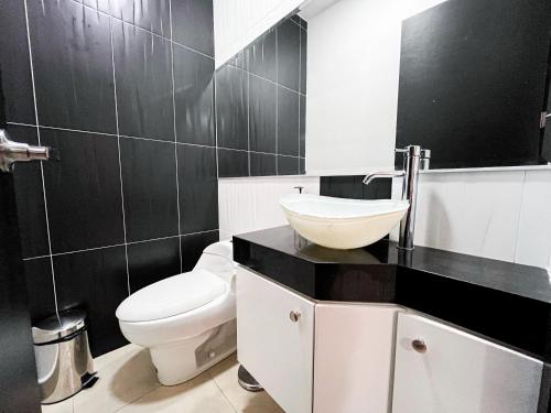 a bathroom with a white toilet and a sink at Casa con Piscina Privada, Asadero Bbq y 4 cuartos en Guayaquil in Guayaquil
