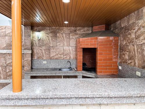 a kitchen with a brick fireplace and a sink at Casa con Piscina Privada, Asadero Bbq y 4 cuartos en Guayaquil in Guayaquil