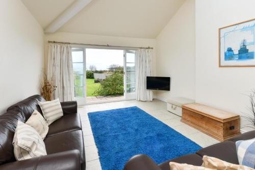 a living room with a leather couch and a blue rug at 1 Coed y Llyn in Abersoch