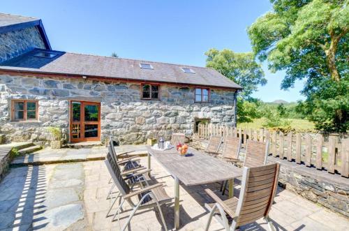 a table and chairs in front of a stone cottage at Maesgwm Barn in Llanfachreth