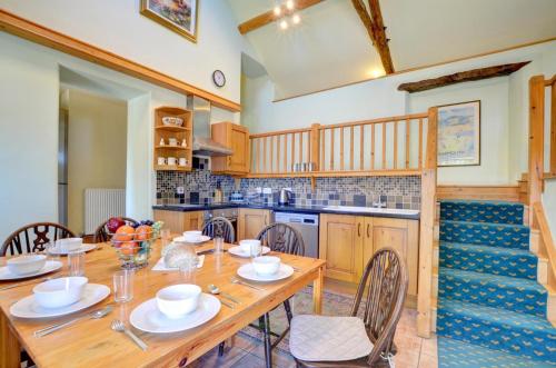 a kitchen with a wooden table and chairs at Maesgwm Barn in Llanfachreth