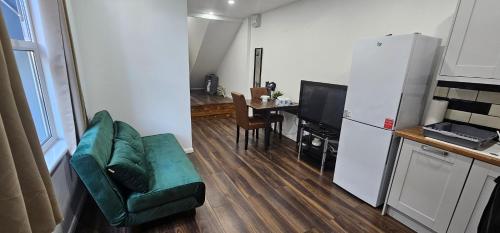 a living room with a green couch and a kitchen at Ground floor outdoor ease in Cardiff